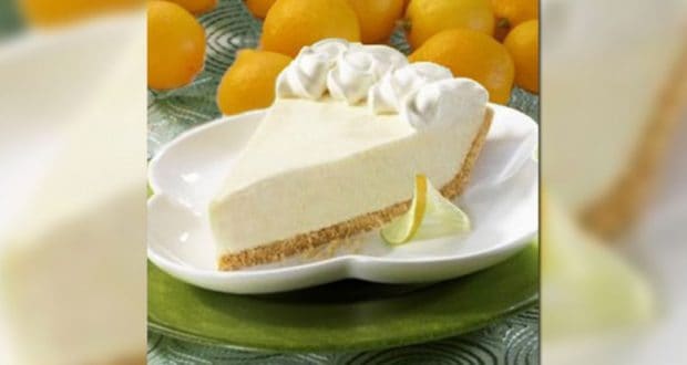 A zesty lemon pie slice topped with whipped cream, plated near fresh lemons—ready for a sweet treat after your park adventure.