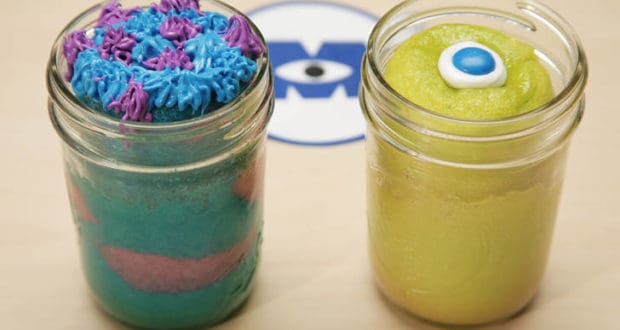 Monsters, Inc.-themed cake jars featuring Mike & Sulley: blue with purple frosting, and yellow with a single eye at Disney Parks.