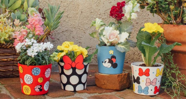 Minnie Mouse-themed flower pots burst with color and blooms, creating a cheerful Disney-inspired patio garden near lush greenery.