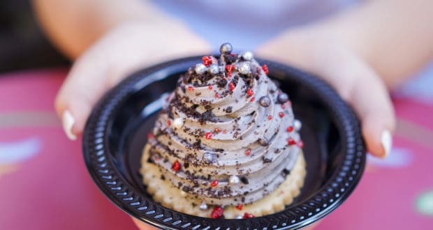 A whimsical plate of Grey Stuff-inspired swirl dessert, crowned with berries and chocolate pearls at a Disney Parks dining table.