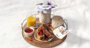 Magical Disney-themed breakfast tray with French toast, raspberries, OJ, card, and paper flowers—Mother’s Day park delight!.