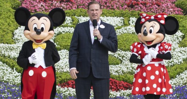 Mickey and Minnie Mouse greet a guest among vibrant flower beds at Shanghai Disney Resort, capturing the magic of Disney.