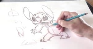 A hand draws Stitch from Disney’s Lilo & Stitch with a pencil on white paper, perfect for Disney fans learning character art.