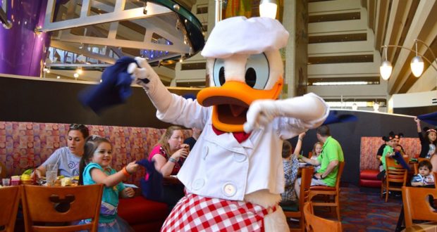 Donald Duck, dressed as a chef, delights families at a vibrant Disney restaurant, capturing the magic of Chef Mickey’s.
