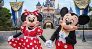 Minnie and Mickey Mouse hold hands before a magical castle, embodying the unforgettable joy of your Disneyland adventure.