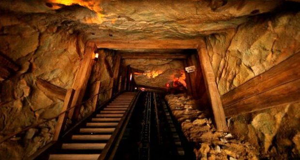 Big Grizzly Mountain Runaway Mine Cars climbs into a shadowy, wooden and rocky mine tunnel at Hong Kong Disneyland.