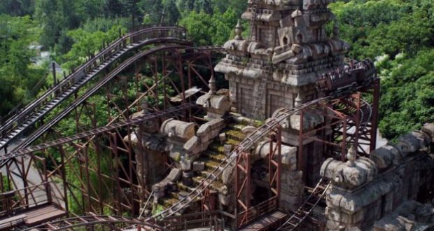 Indiana Jones roller coaster races through ancient temple ruins, surrounded by lush greenery at Disneyland Paris.