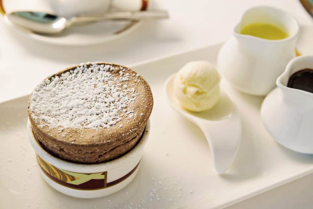 A decadent Palo-inspired chocolate soufflé, dusted with powdered sugar, served with vanilla ice cream and Disney-themed sauces.