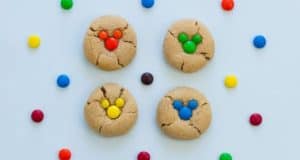 Mickey-shaped cookies topped with colorful candies are surrounded by a rainbow of treats, perfect for Disney fans to enjoy.