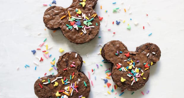 Three Mickey Mouse-shaped brownies with colorful sprinkles, inspired by Disney Parks treats, on a white surface.