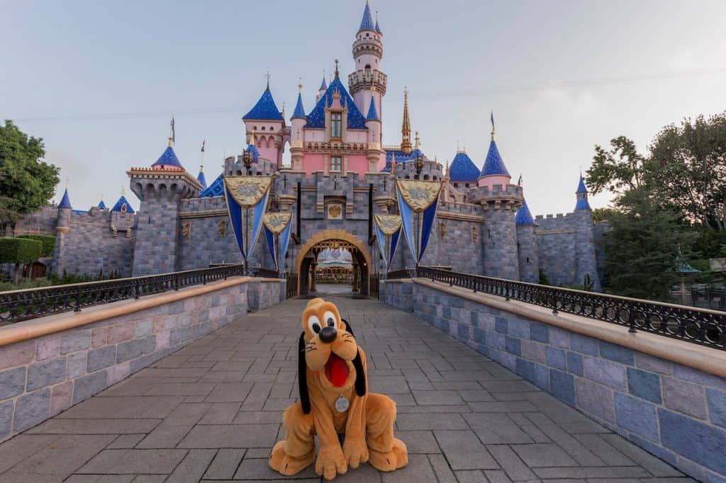 Pluto poses in front of Sleeping Beauty Castle at Disneyland, joining the International Dog Day festivities under sunny skies.