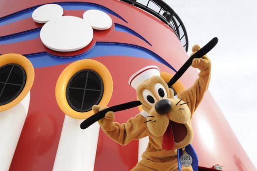 Pluto beams in front of the giant Mickey Mouse logo on a Disney Cruise Line smokestack, marking International Dog Day Disney-style.