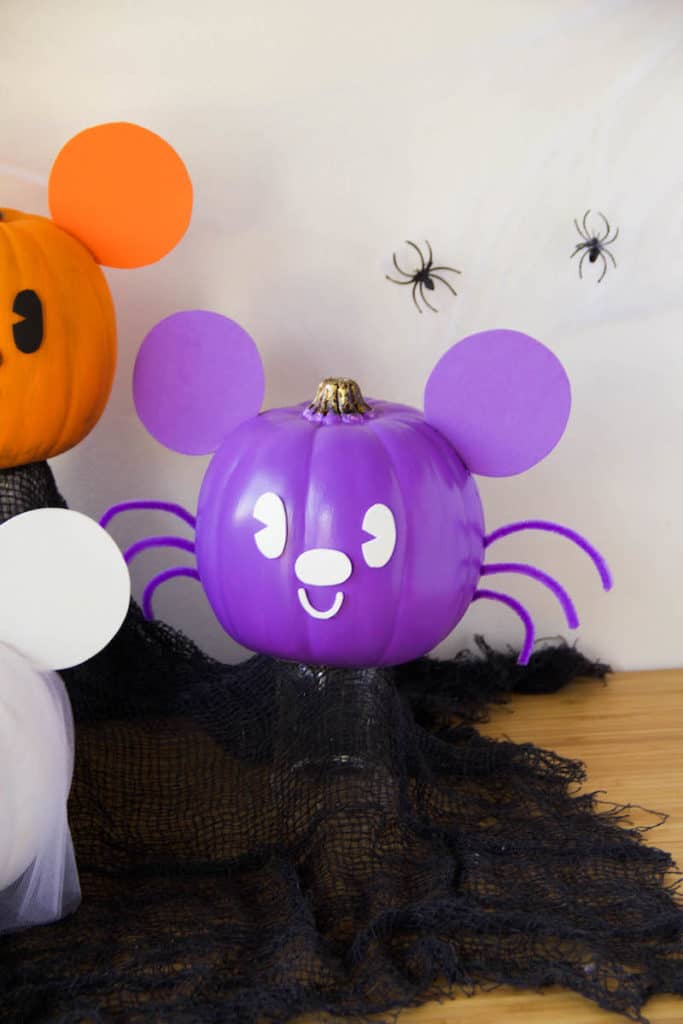 A purple pumpkin styled as a bat, with big ears and pipe cleaner wings, channels Disney's Halloween magic on a white backdrop.