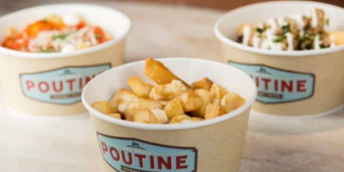 Three containers of poutine on a table. The front container is filled with cheese curds and gravy on fries, while the other two in the background appear to have additional toppings. Each container is labeled "Poutine.