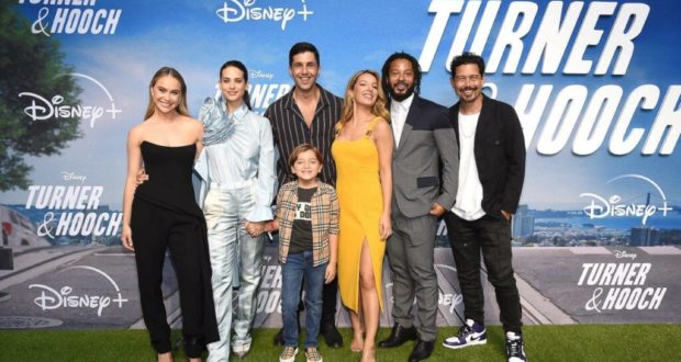 Cast and crew members from "Turner & Hooch" gather in front of the signature Disney+ premiere backdrop, smiling for photos as fans and guests celebrate the series launch.