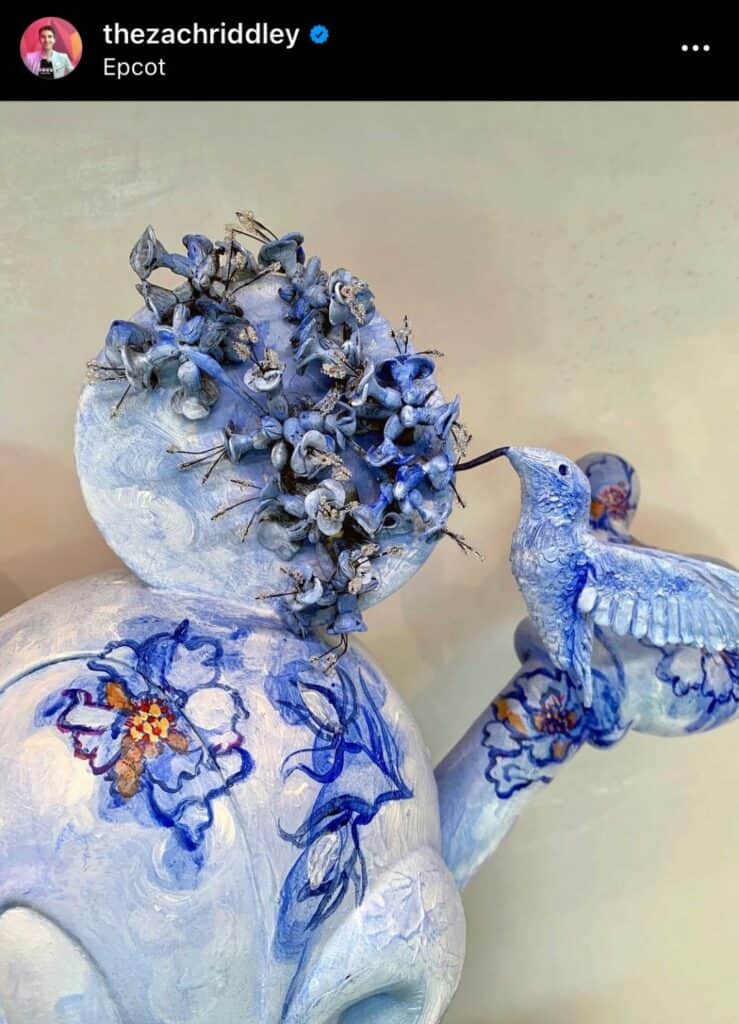 A whimsical blue and white ceramic Mickey Mouse head, adorned with delicate flowers and a charming hummingbird, stands out as an enchanting art piece at the Creations Shop in Disney World. This artwork celebrates the timeless magic of Mickey as Disney’s beloved muse.