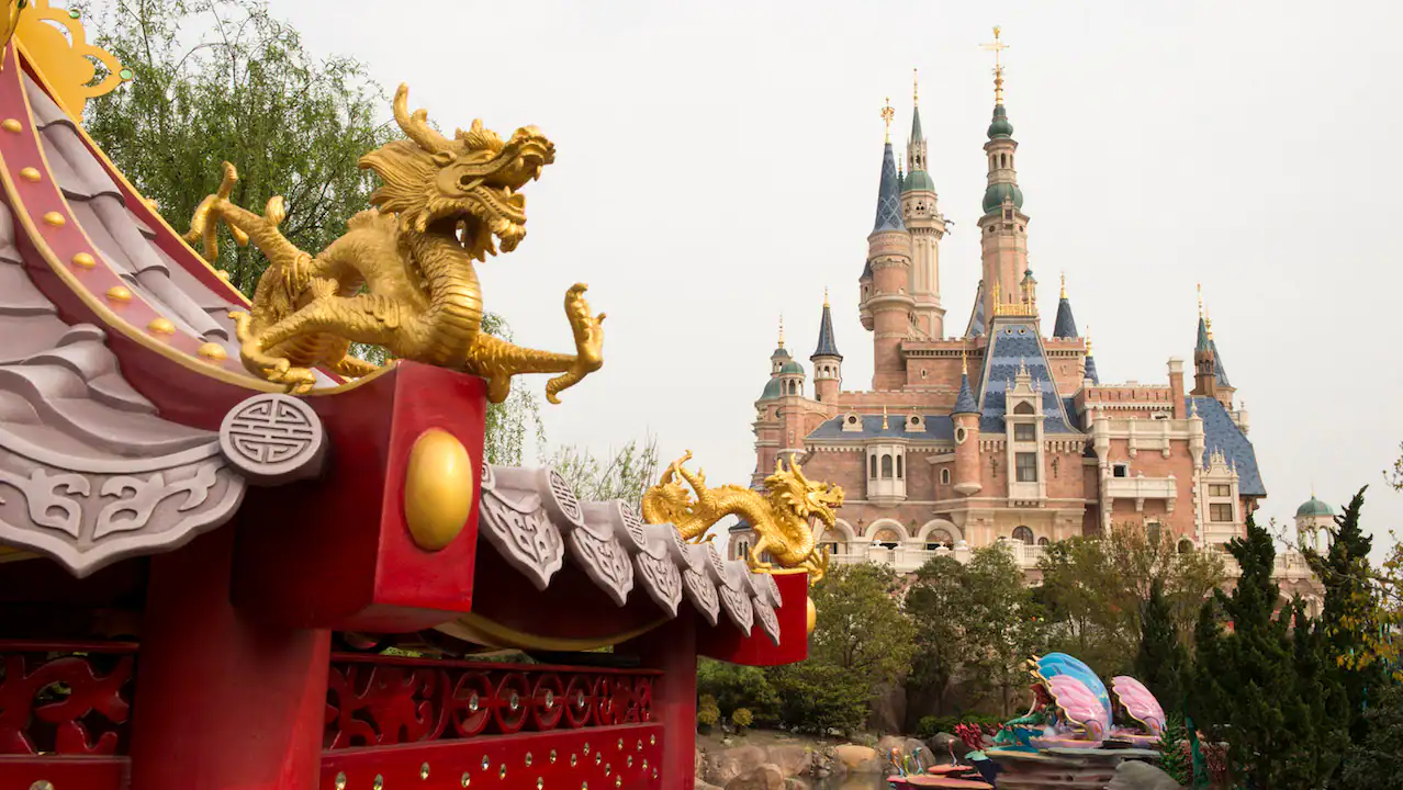 a chinese dragon in the foreground with the castle in the background at shanghai disneyland 
