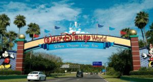 Walt Disney World entrance with Mickey and Minnie, vibrant flags, “Where Dreams Come True,” energizing buzz about a fifth gate.