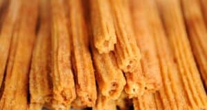 Close-up of several golden-brown churros stacked together, their crispy, textured exterior coated with sugar. These delightful treats evoke the magic of a Disney Christmas morning, each bite capturing the joy and wonder of the season.