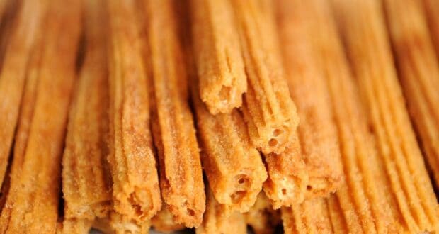 Close-up of several golden-brown churros stacked together, their crispy, textured exterior coated with sugar. These delightful treats evoke the magic of a Disney Christmas morning, each bite capturing the joy and wonder of the season.