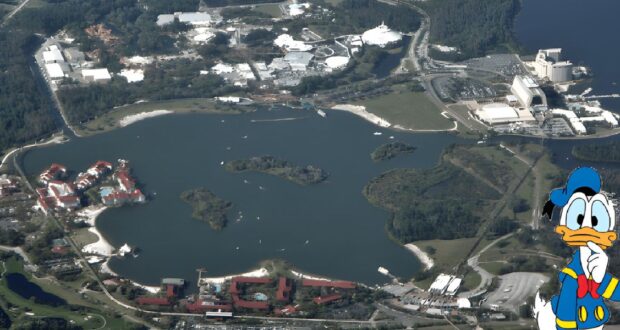 Aerial view of Epcot at Disney World, part of the sprawling 43 square miles that make up the size of Disney World, showcasing a large central lake with various buildings and attractions around it. Donald Duck, in his classic sailor outfit, is illustrated in the bottom right corner. Lush greenery and roads surround the site.