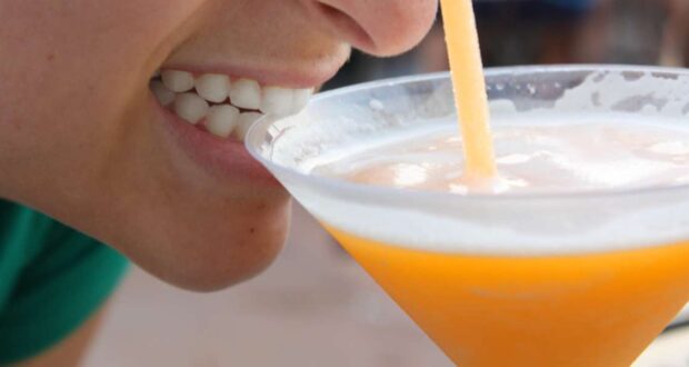 A woman drinking a cold alcoholic drink at EPCOT