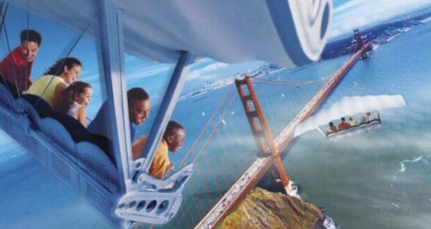 A group of people on the Soarin' ride at EPCOT simulates flying over the Golden Gate Bridge, with passengers smiling and leaning forward. The scene includes a blue sky and ocean below, capturing all the exhilaration of this aerial adventure.