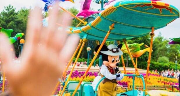 A guest waves at Mickey Mouse on a parade float at Disneyland Paris