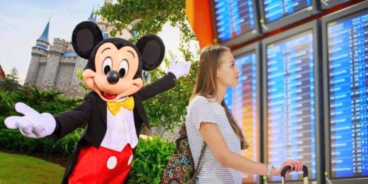 A person stands in front of a flight information board, looking up at the screen. To the left, an image of Mickey Mouse at a Disney theme park with a castle in the background adds a touch of magic to the scene.