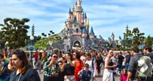 A bustling day at disneyland with visitors enjoying the view of the iconic fairy tale castle.