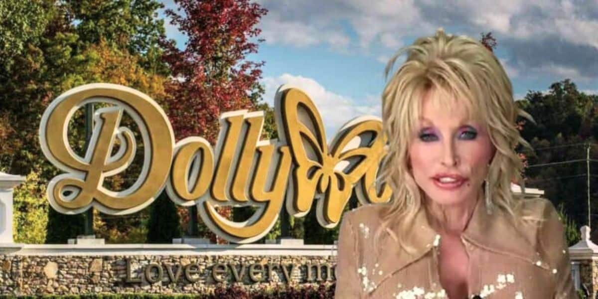 A person with blonde hair and wearing a beige outfit is standing in front of the Dollywood entrance sign. The sign features the word “Dollywood” in gold lettering with a butterfly design and the tagline “Love every moment.” The background includes trees and a cloudy sky.
