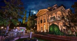An eerie, moonlit night at a grand, haunted mansion, complete with an abandoned carriage out front.