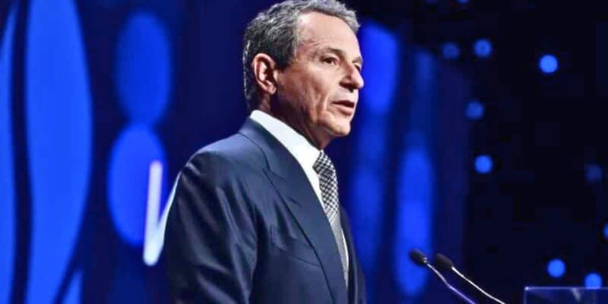 Bob Iger speaking at a podium against a blue-lit backdrop.
