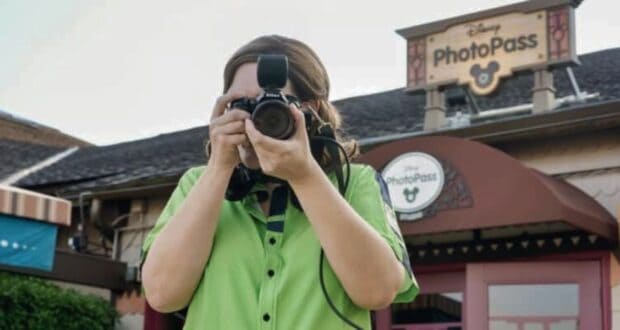 A Disney cast member taking a picture with a PhotoPass camera.