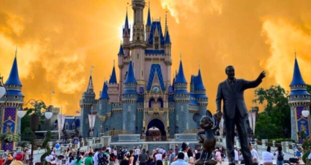 Sunset hues cast a dramatic backdrop over the iconic cinderella castle and the statue of walt disney and mickey mouse at a bustling disney theme park.