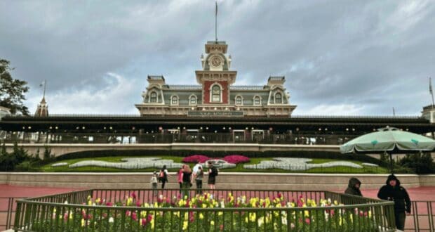 The Walt Disney World Railroad boarding station near the entrance of Magic Kingdom on Main Street, U.S.A., during a cloudy day with guests and security cast members.