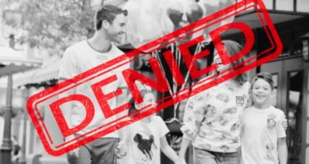 Black and white photo of a smiling family walking outdoors, reminiscent of a joyful day at Disney World. They consist of two adults and two children, holding balloons. A large red "DENIED" stamp overlays the image.