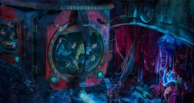 A vibrant, underwater-themed amusement park ride with two submarine pods filled with excited riders. The scene features red curtains, colorful lights, aquatic decorations, and an animatronic figure dressed in vibrant costume amidst the water-themed background.