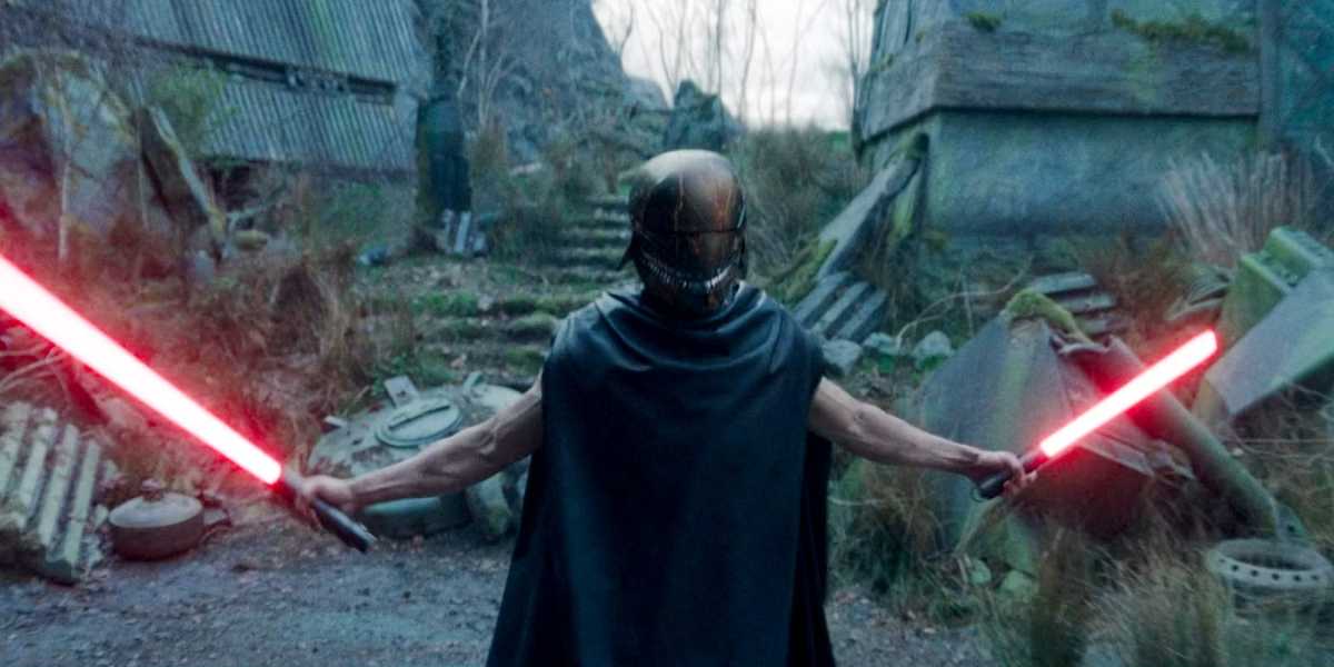 A figure stands in a desolate, overgrown area, holding two red lightsabers with arms outstretched. The person is wearing a helmet and cape, adding to an ominous presence amidst the rundown, post-apocalyptic surroundings.