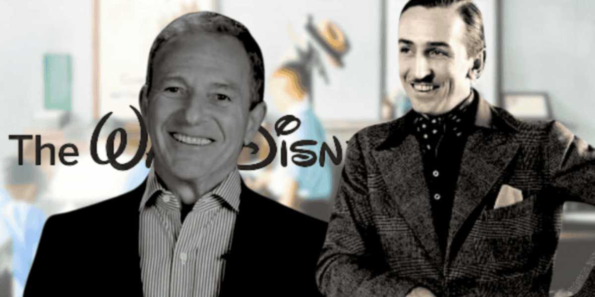 A grayscale photo of two smiling individuals standing in front of the Disney logo. One person is in a suit, and the other in a polka dot shirt with a jacket. The background is blurred, showing a hint of colorful artwork.
