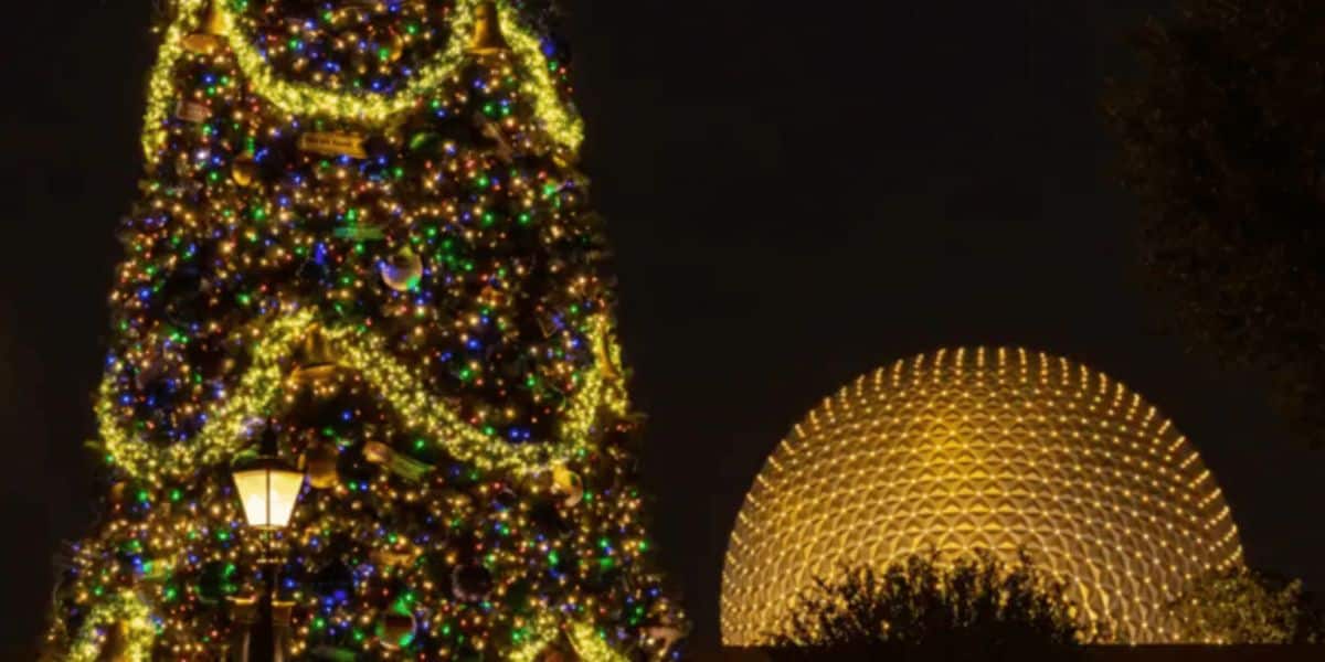 A large Christmas tree adorned with multicolored lights stands illuminated at night next to a glowing geodesic dome structure. The tree is decorated with festive ornaments, and a streetlamp is visible in the foreground.