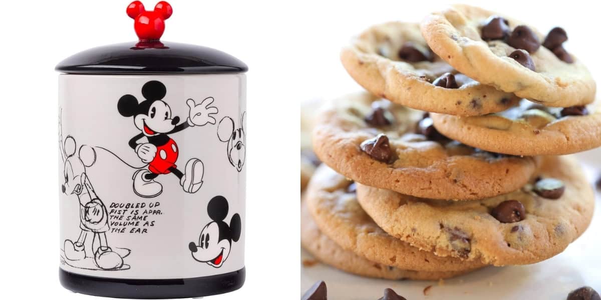 A cookie jar featuring Mickey Mouse drawings and a bright red knob shaped like Mickey's head stands beside a stack of freshly baked chocolate chip cookies. The jar is white with black and red accents, and the cookies display delicious chocolate chunks.