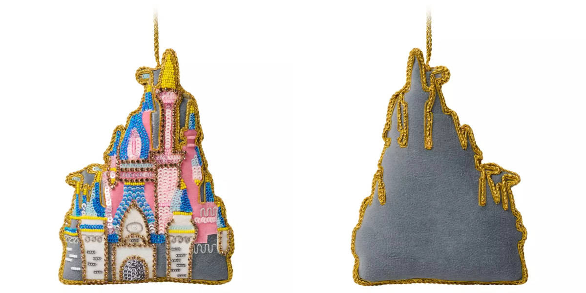 A two-sided image of a handmade fabric ornament shaped like a fairy tale castle. The front features colorful embroidery with pink, blue, and gold accents, while the back is plain with a gold outline.