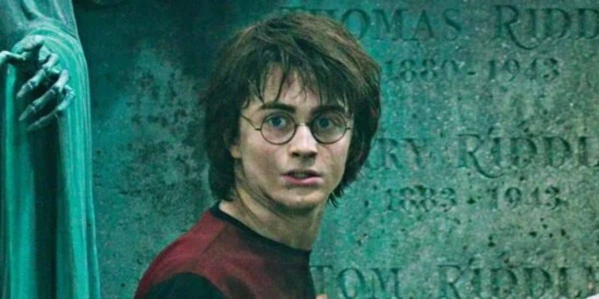 Harry Potter stares ahead in fear in front of a tombstone