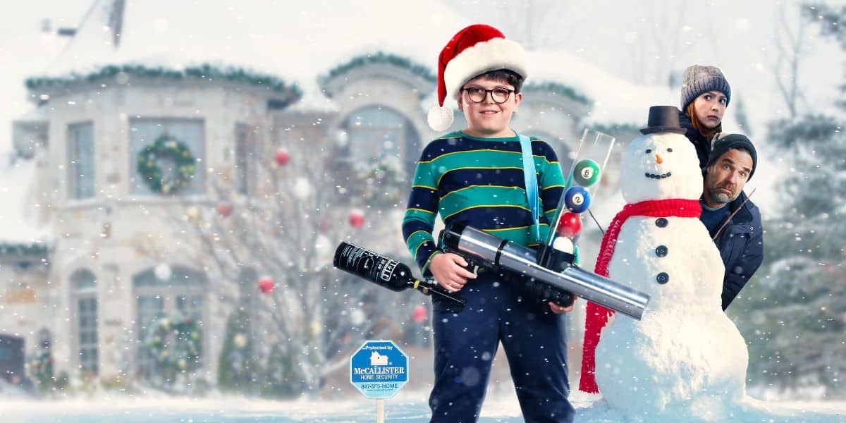 Max Mercer (Archie Yates) with a toy gun while wearing a Santa hat in the snow in the poster for 'Home Alone'