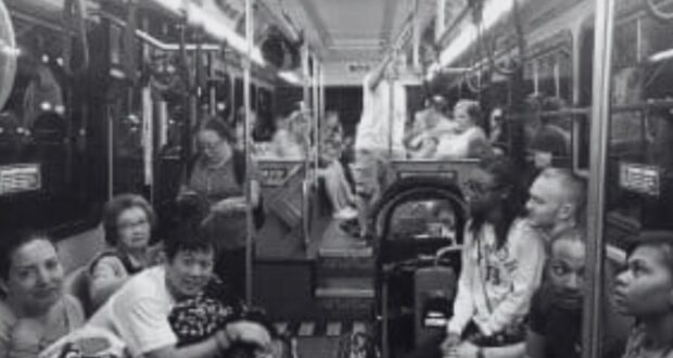 A black and white photo of people sitting inside a Disney bus.