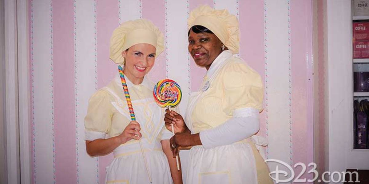 Main Street Confectionery cast members stand in front of the candy stripe wall at Magic Kingdom