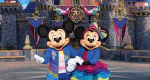 Mickey Mouse and Minnie stand in front of a castle adorned with Disneyland70 decor.