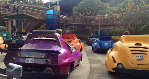 People drive colorful, futuristic cars on Autopia.