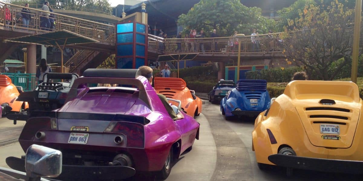 People drive colorful, futuristic cars on Autopia.